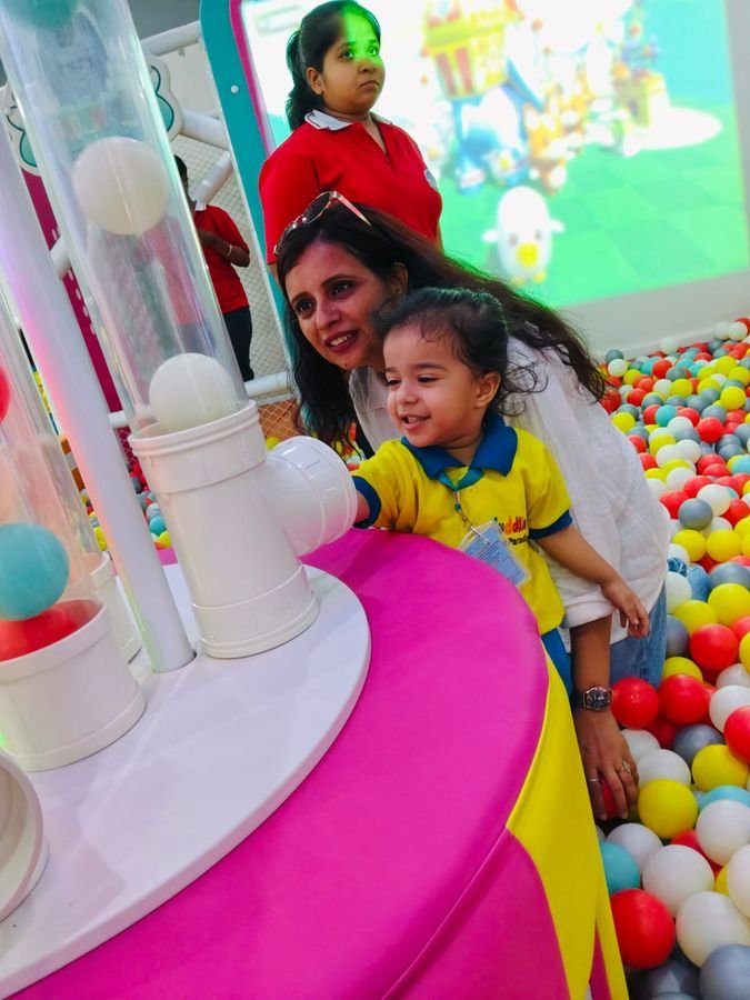 A parent and child playing together in a ball pit during an outing