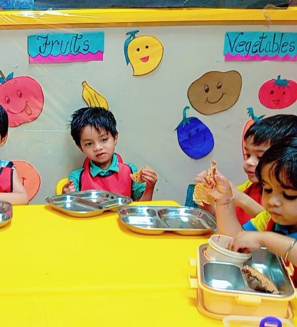 A child eating beside the fruits and vegetables wall charts