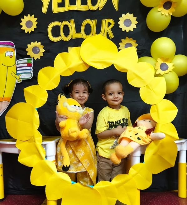 Two children in a Yellow Colour Day photo frame, decorated with sunflowers and balloons