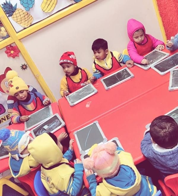 Children practising writing on slates at a red table