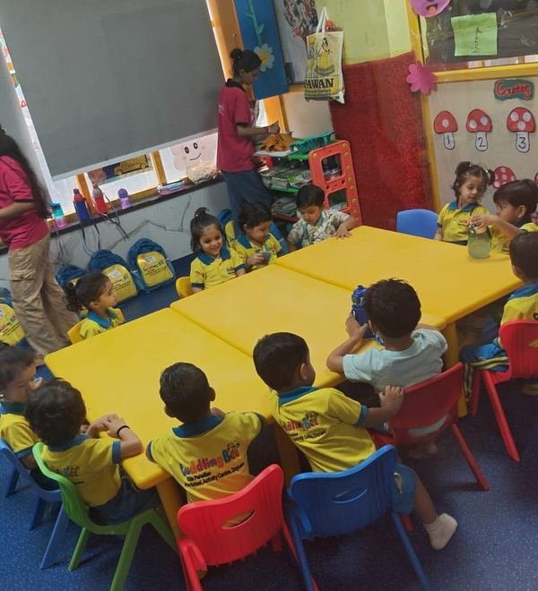 A facilitator with children at snack time beside the counting wall display