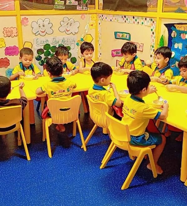 Children sitting together at yellow tables during snack time